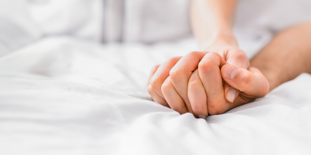 A,close up,shot,of,two,hands,intertwined,on,a,white